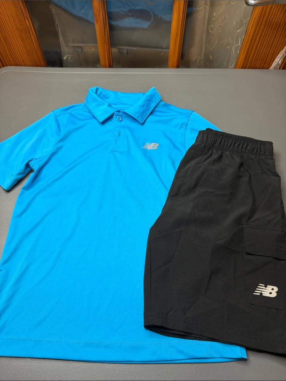 Kid’s New Balance Bright Blue Polo and Black Athletic Shorts Set. Size: 8